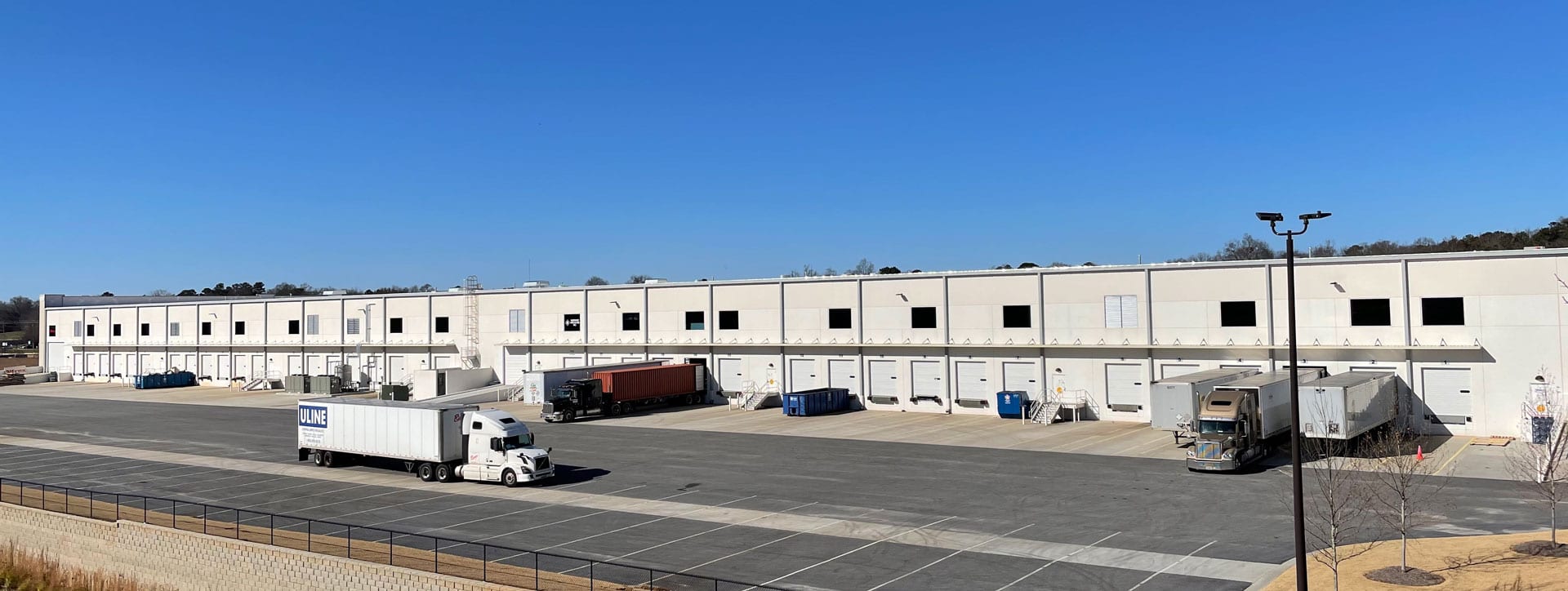 A large warehouse with cars parked in front of it.