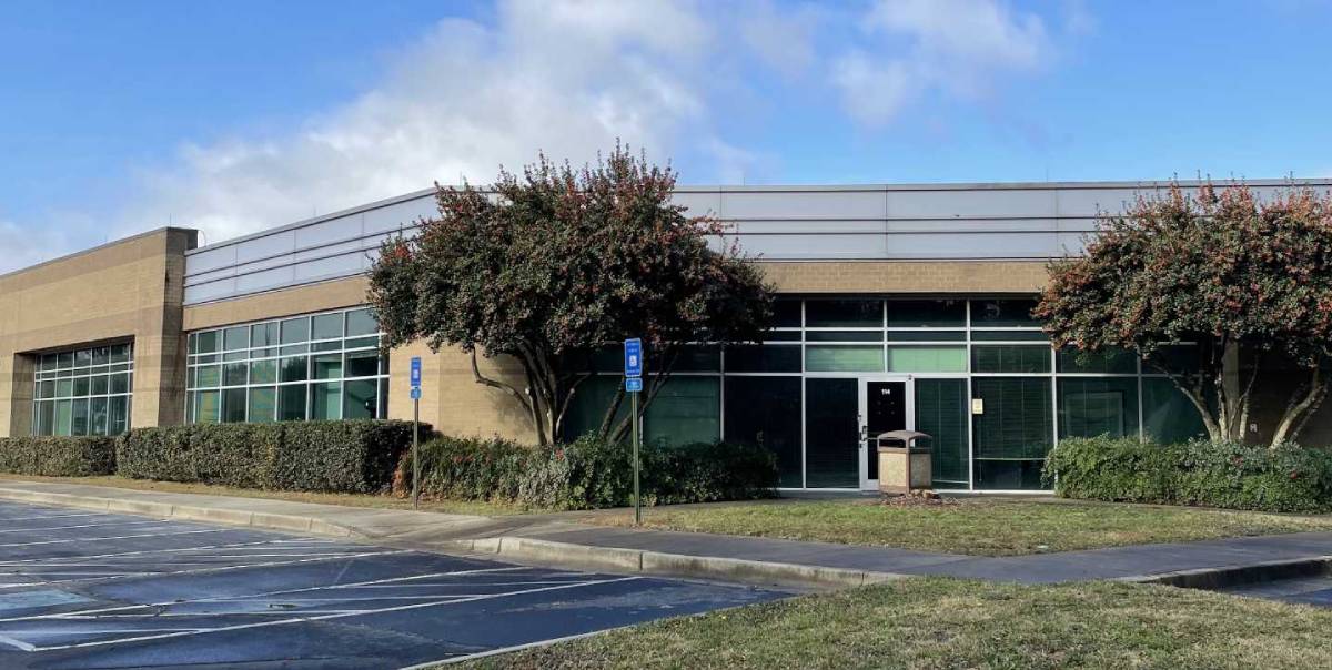 A building with trees and bushes in front of it.