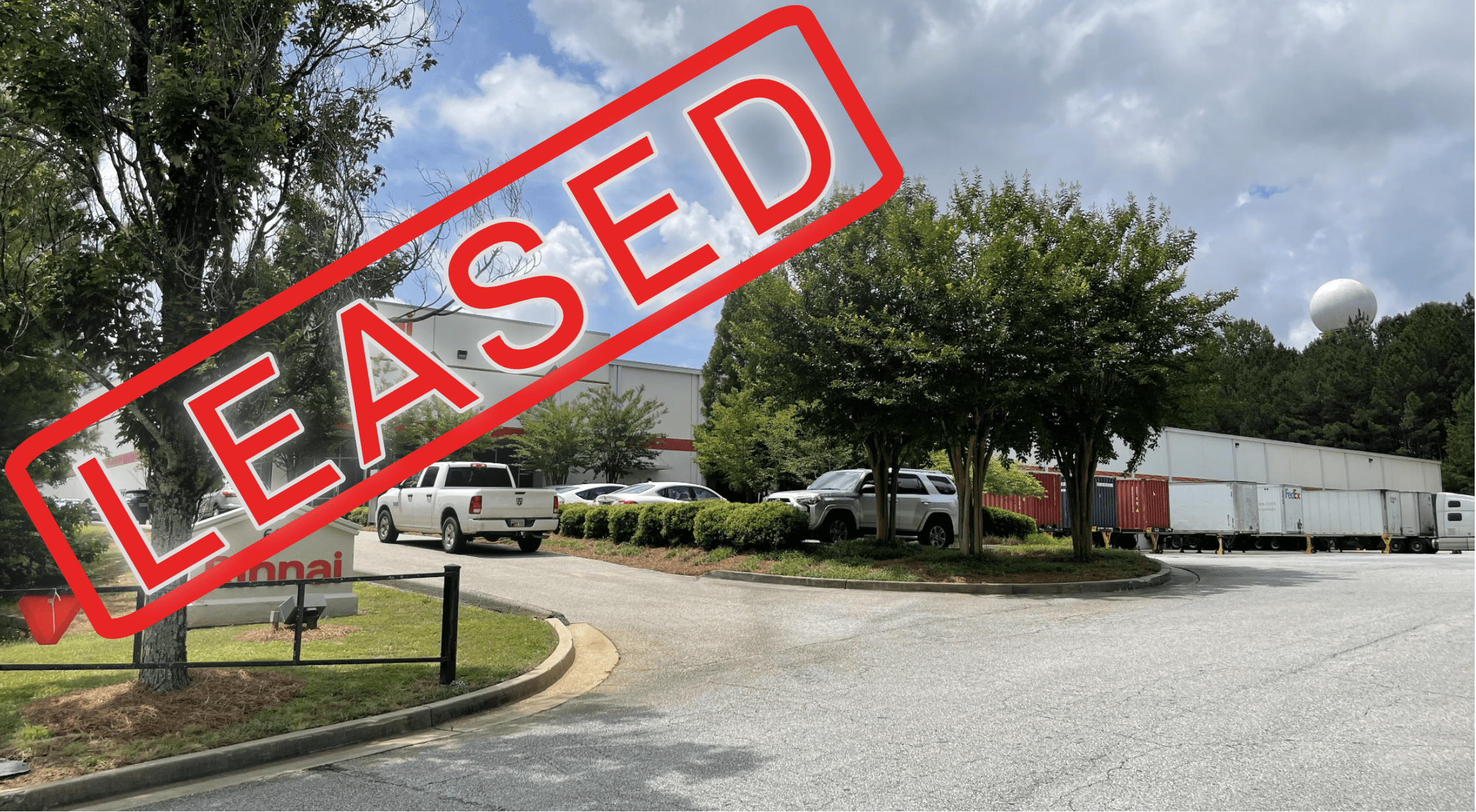 A red sign is in front of some cars parked on the side of a road.